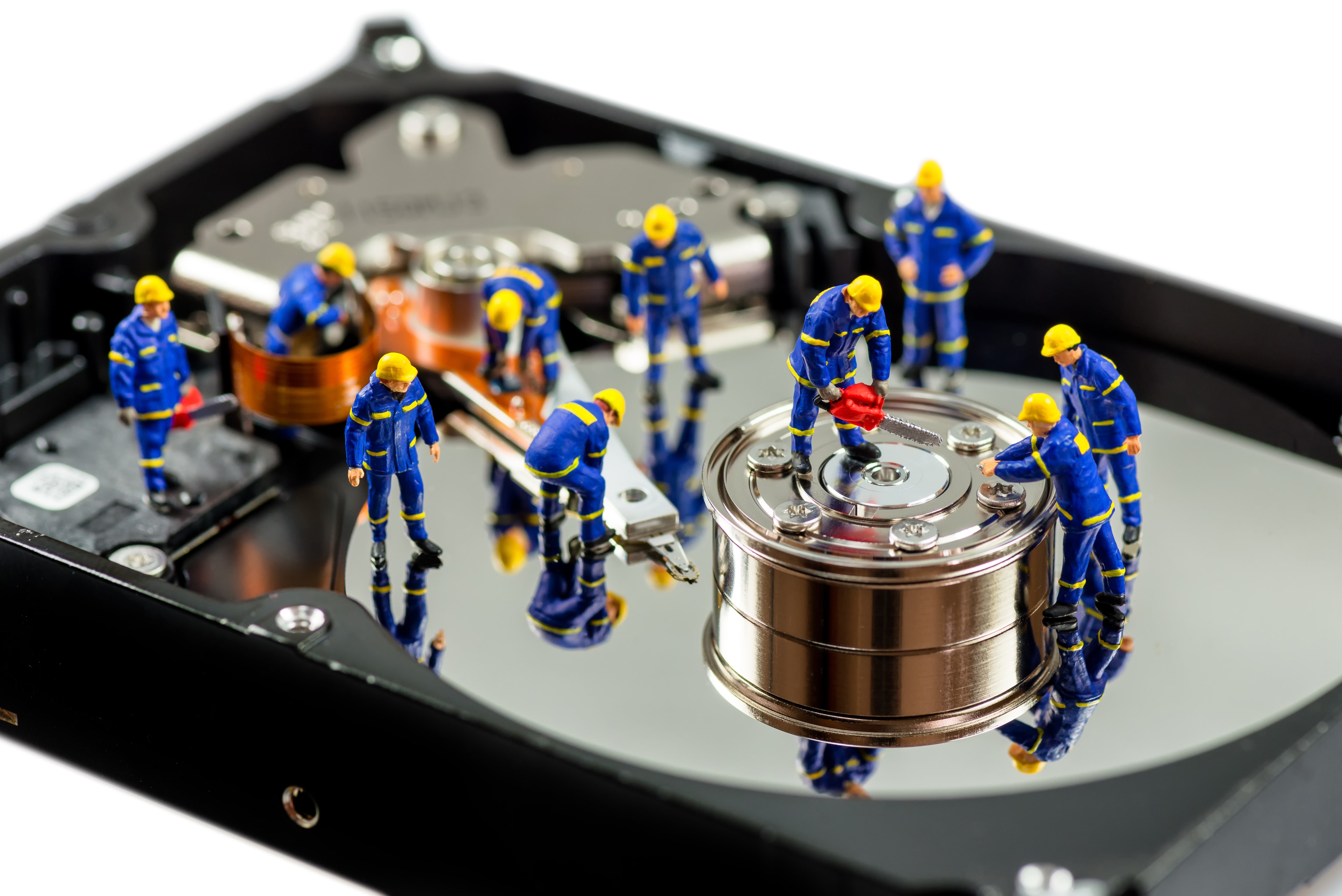 Miniature engineers working on a hard drive — representing our meticulous recovery process